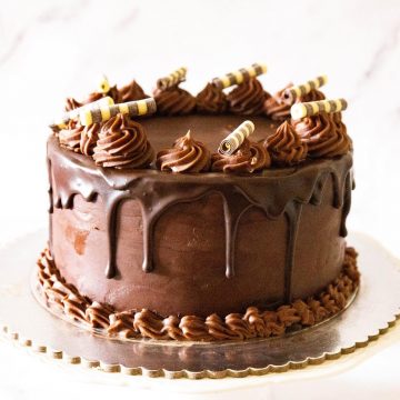 A frosted chocolate cake on a cake board.