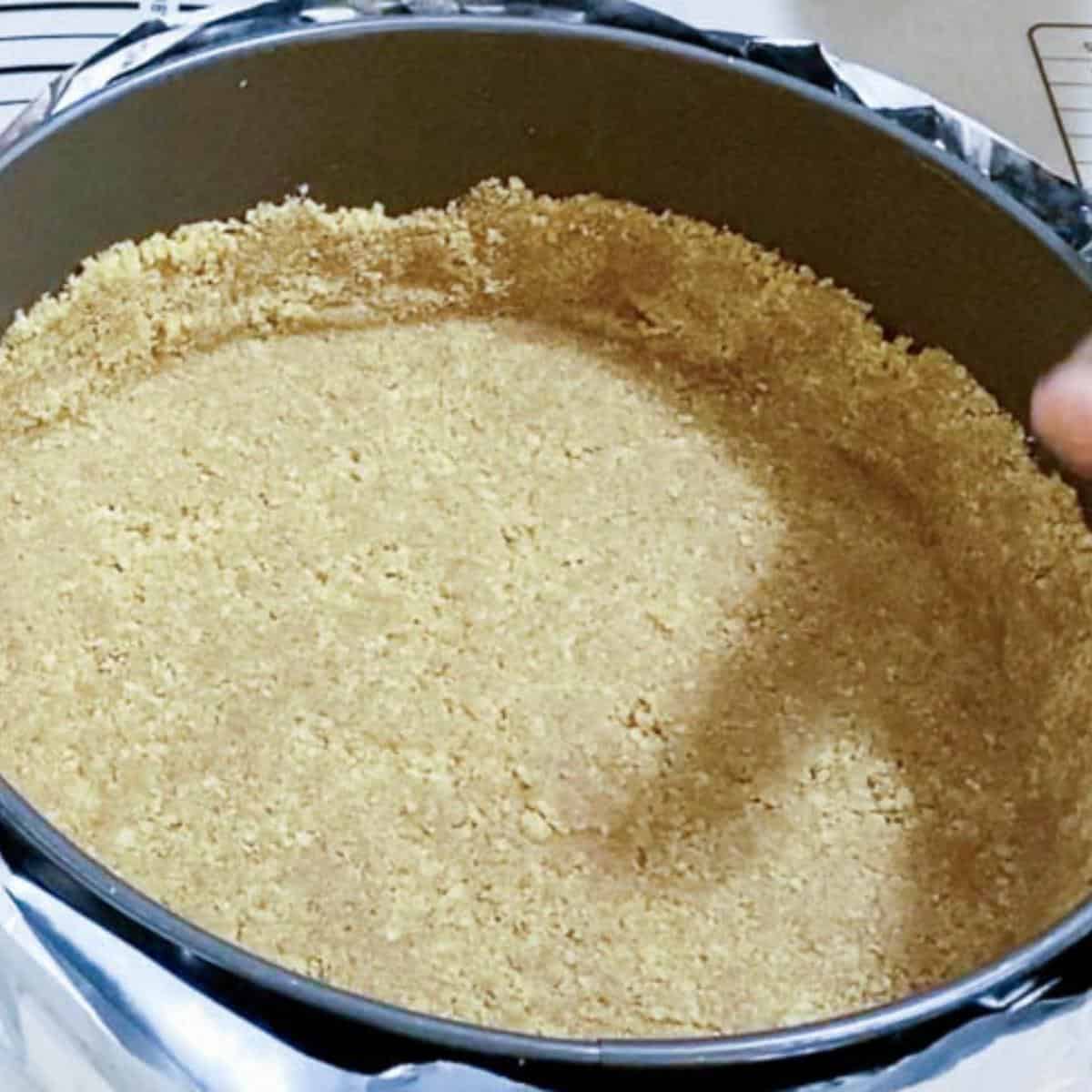 A spring form pan with cookie crust for cheesecake.