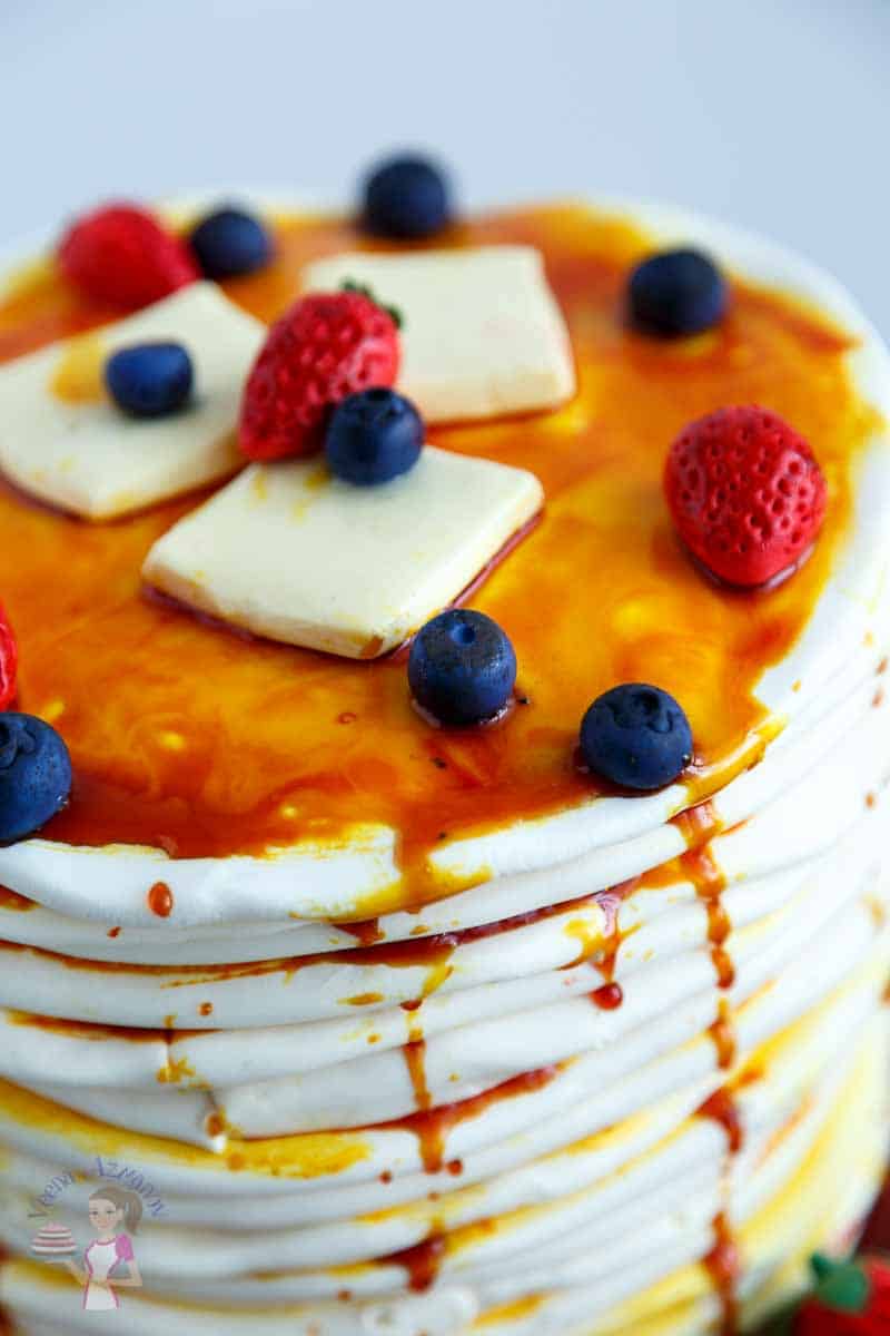 A close up of a cake decorated like a stack of pancakes.