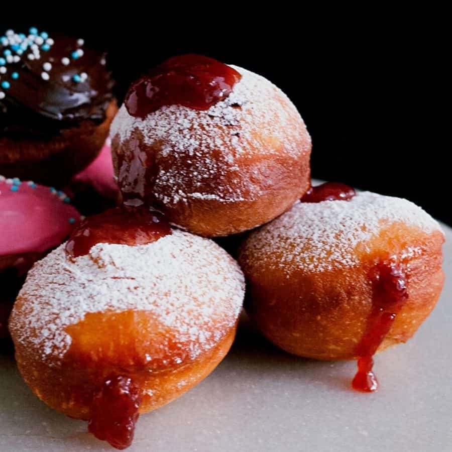 Donuts on a table with strawberry jam.