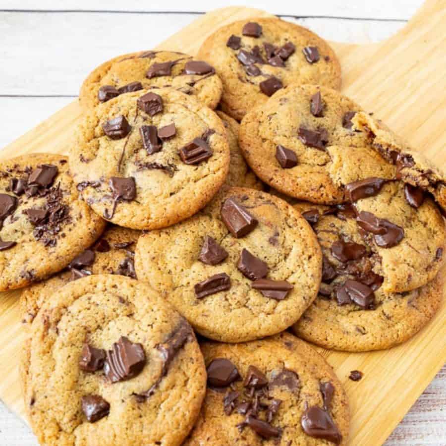 Chewy chocolate chip cookies on a wooden board.