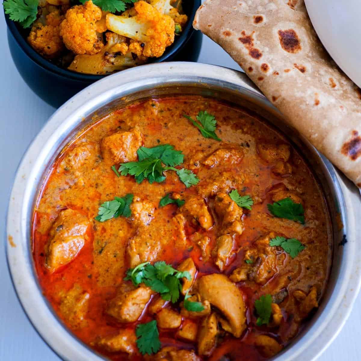 A pot with chicken curry and chapati.