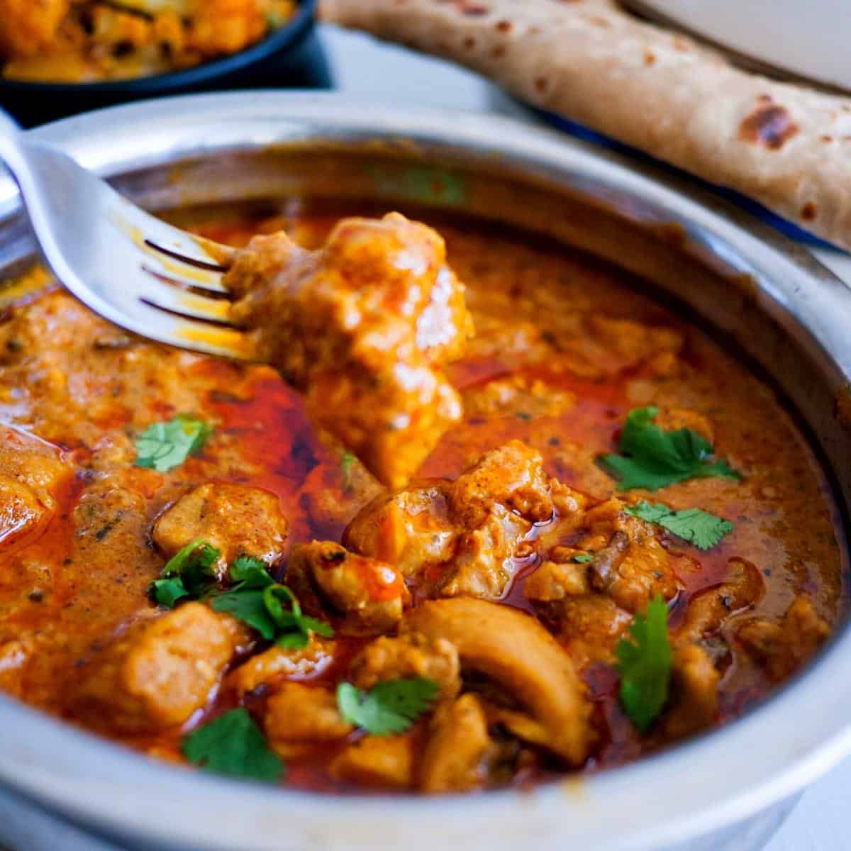 A pot with chicken curry and a fork.