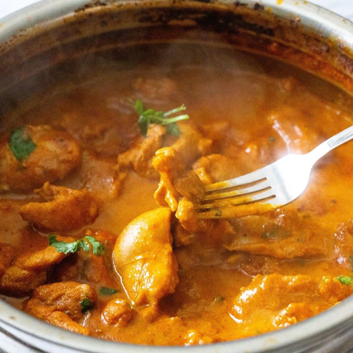 A steaming pot of curry and a fork.