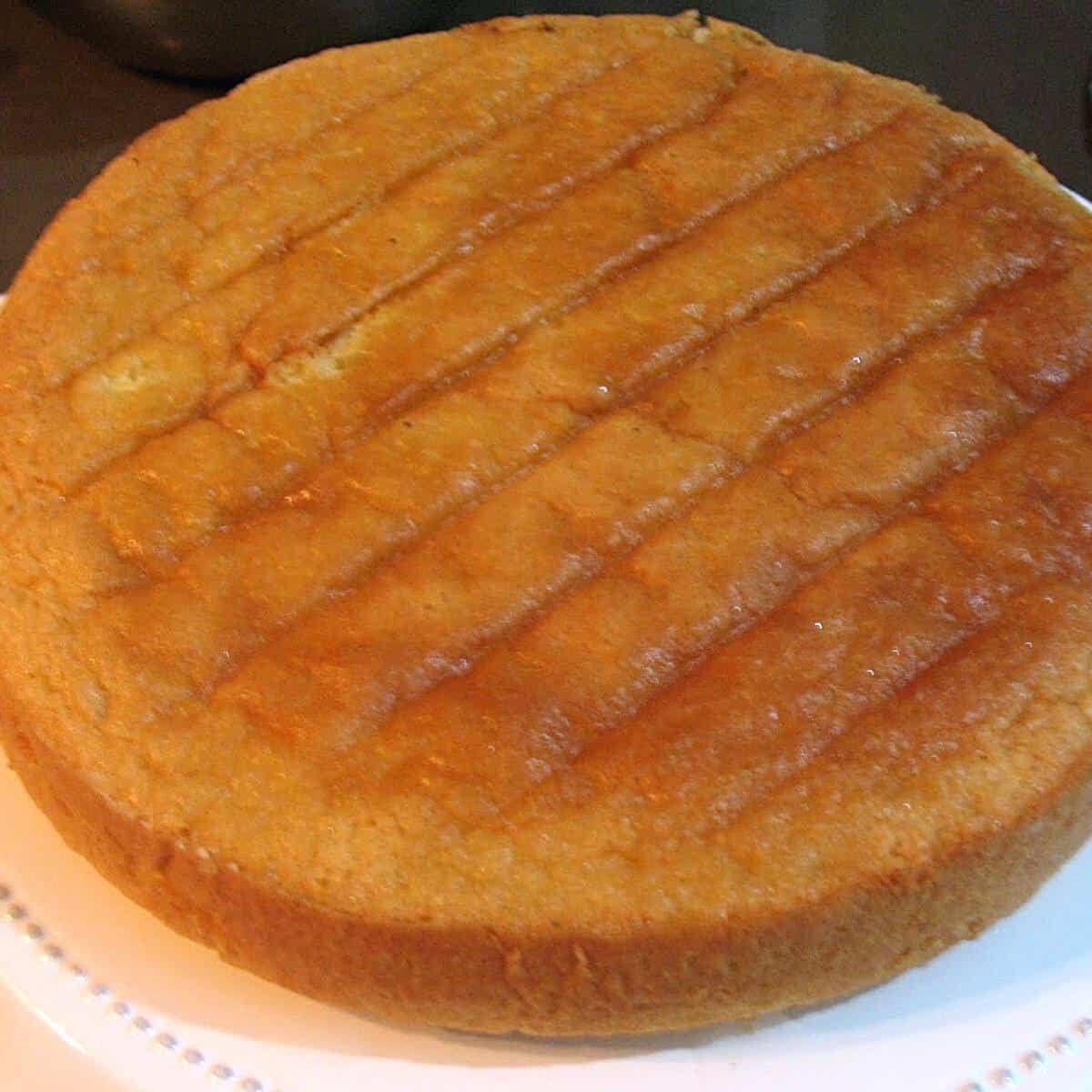 A baked genoise cake on the cake stand.