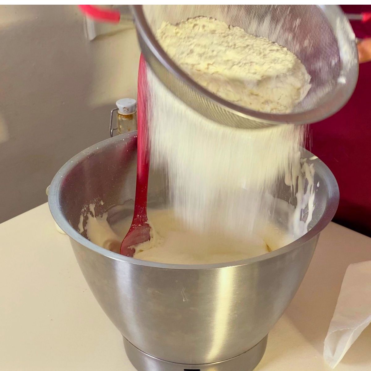 Sifting flour into whipped eggs for sponge batter.