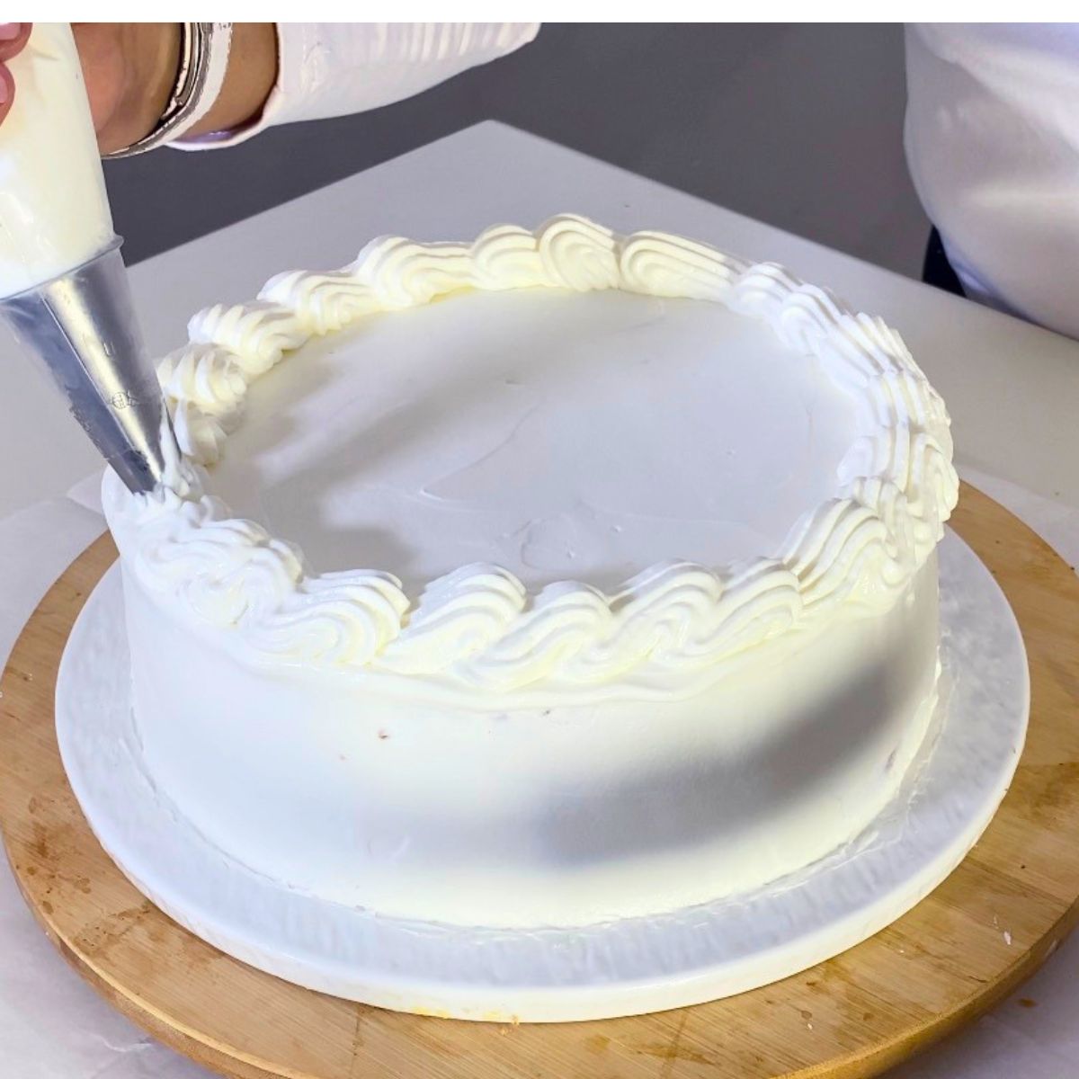 Piping whipped cream on a cake.