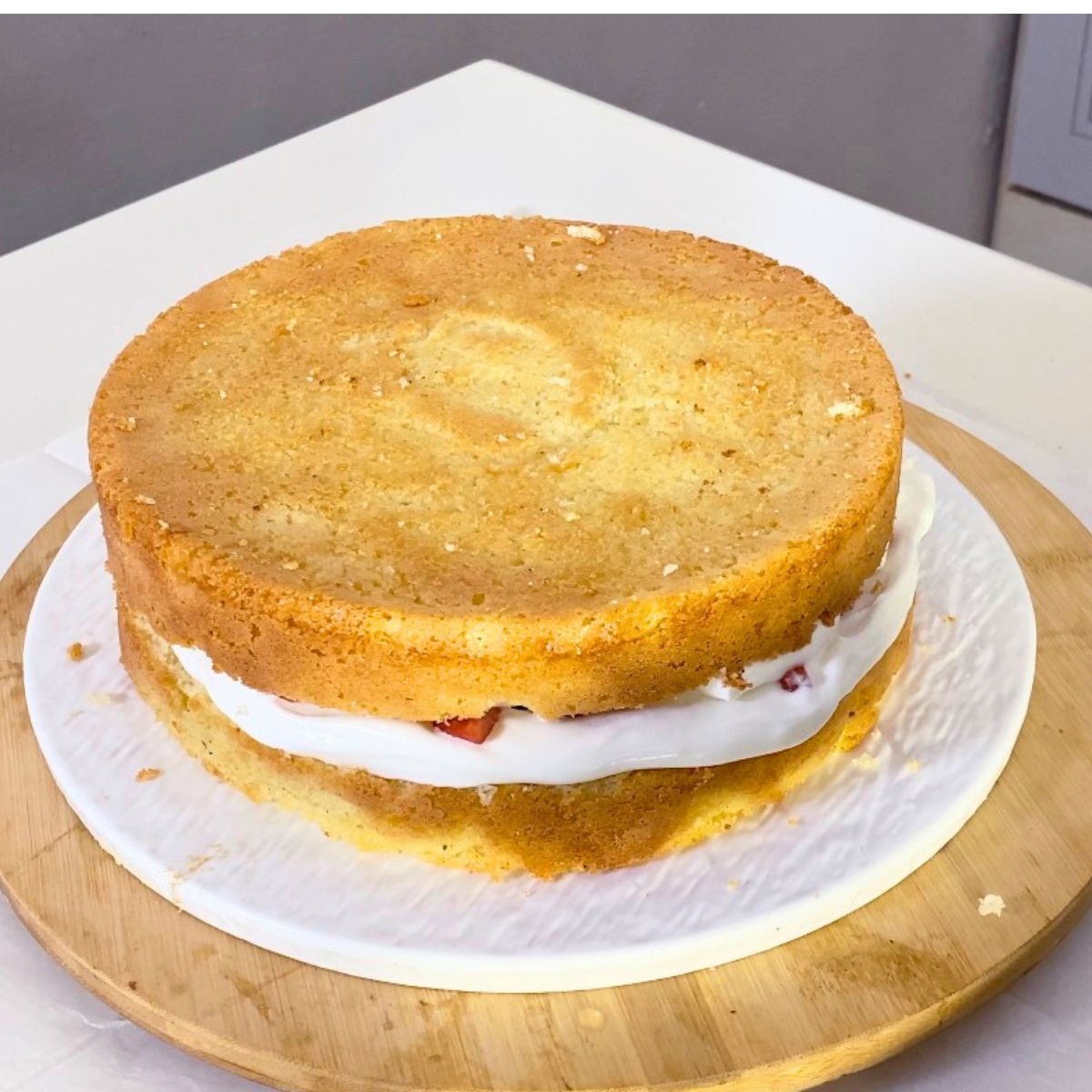 Layering the sponge with whipped cream and strawberries.