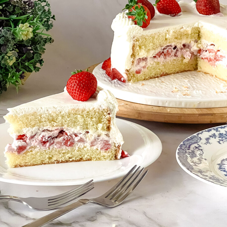 A slice of light sponge cake with heavy cream and strawberries.
