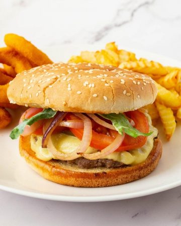 Burgers on a plate with fries and rings.