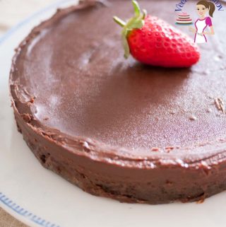 An image optimized for social media sharing for this flourless chocolate cake aka gluten free chocolate cake. Showing the full cake garnished with a strawberry.