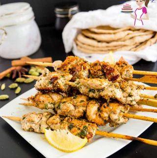 Chicken kebab skewers stacked on a plate.