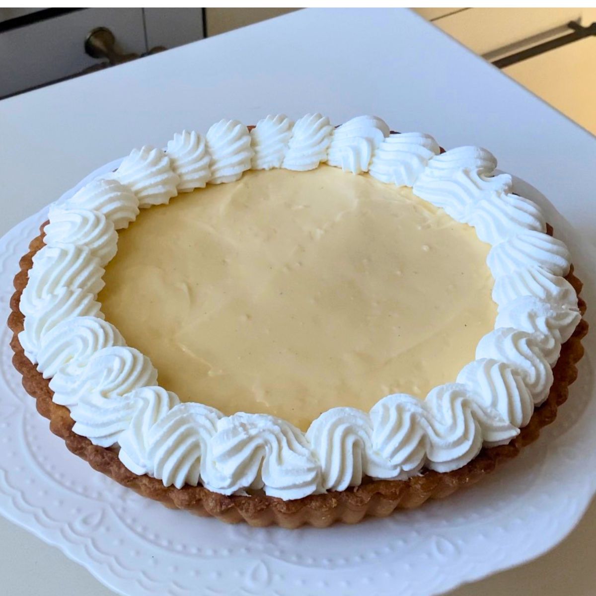 A tart with whipped cream swirl around the edge.