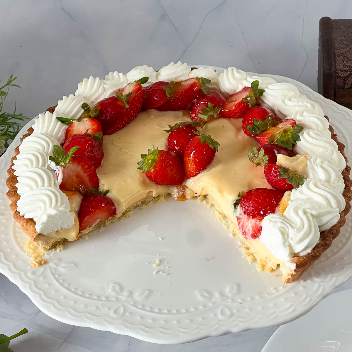A cake stand with fresh strawberry pastry cream tart.