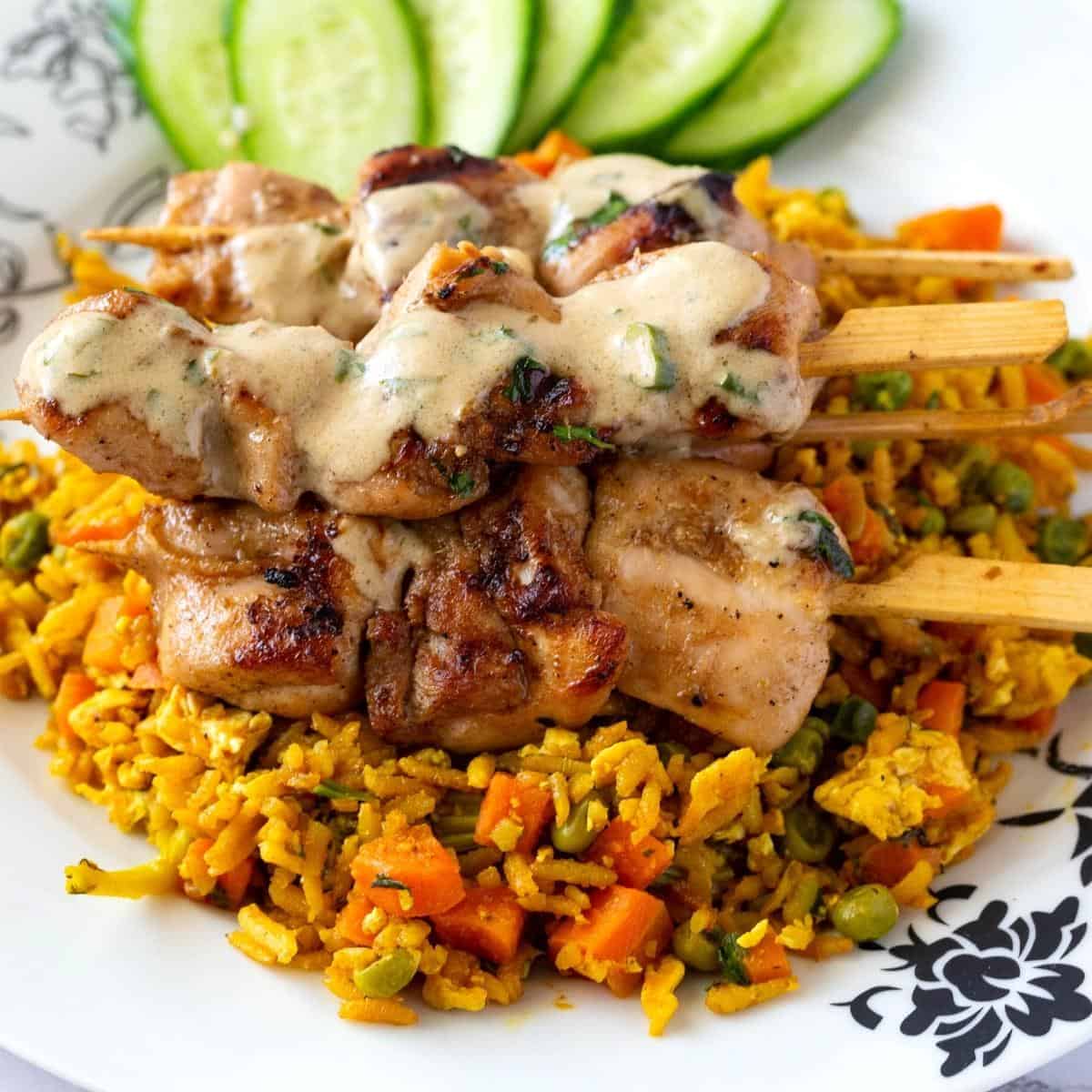 A platter with rice and chicken skewers.