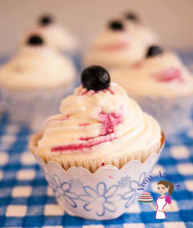 A blueberry cupcake with cream cheese frosting.
