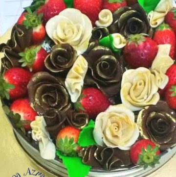 A bowl with chocolates roses and fresh strawberries.