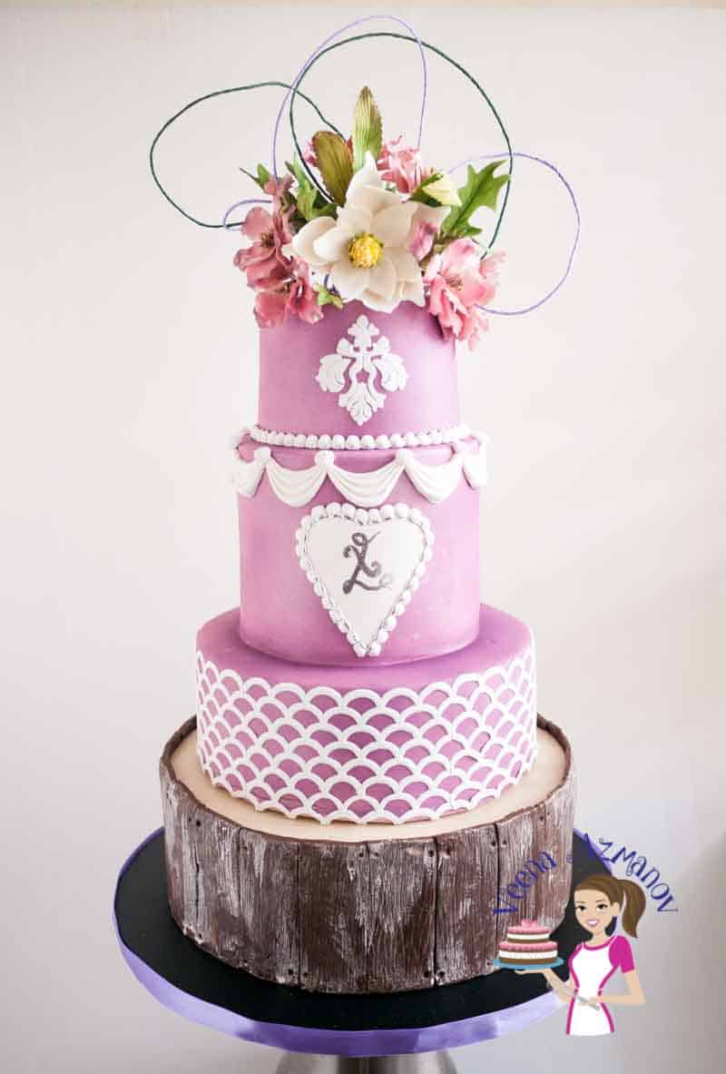 A wedding cake decorated in a violet magnolia theme.