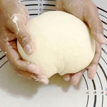 Hands holding pizza dough.