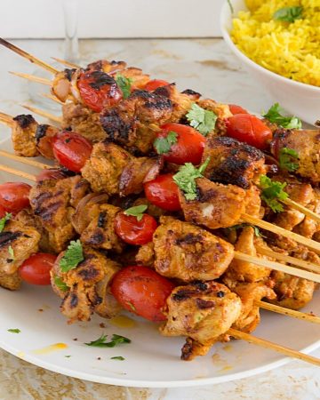 Stack of chicken kebabs on the table with rice.