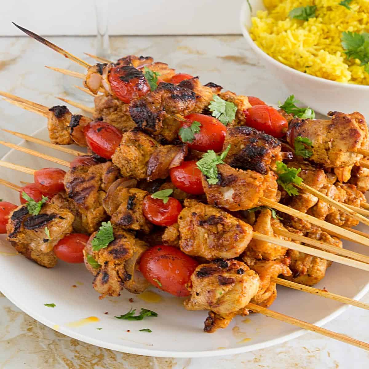 Stack of chicken kebabs on the table with rice.