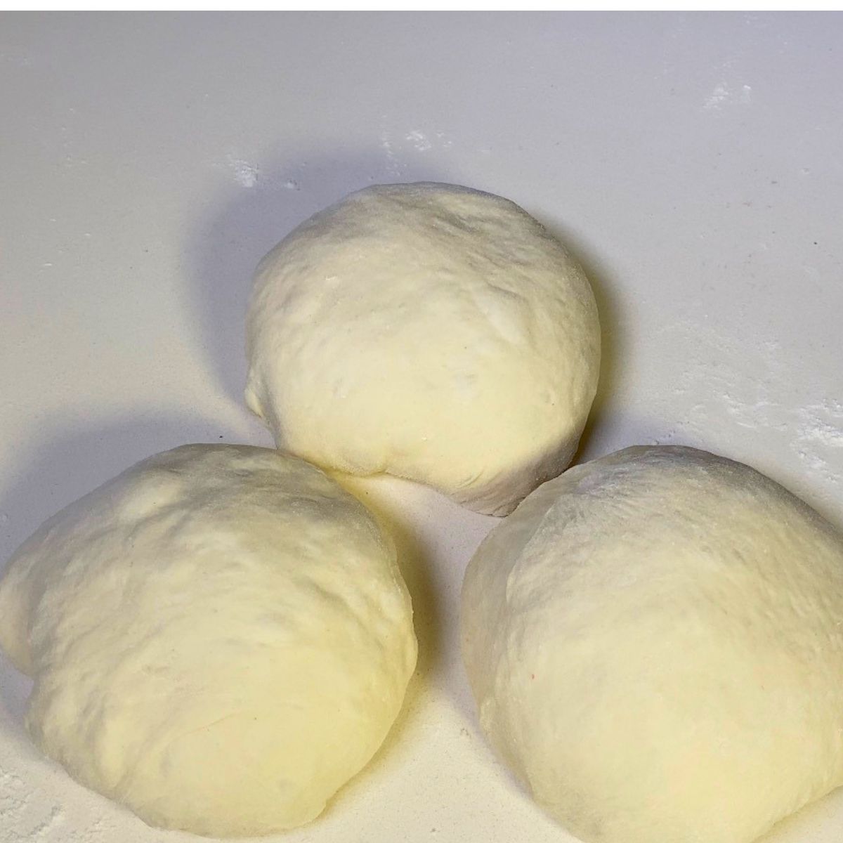 Three balls of pizza dough on the tabl.e