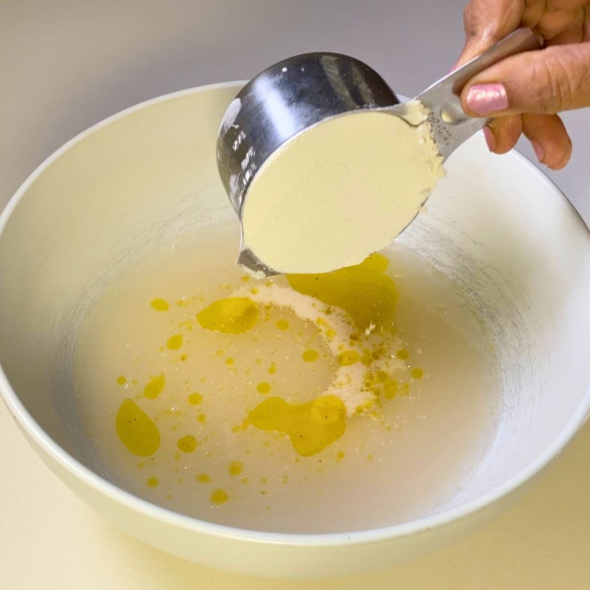 Adding flour to water to make dough.