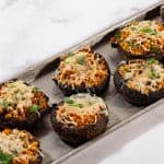 A serving dish with pesto stuffed mushrooms. .