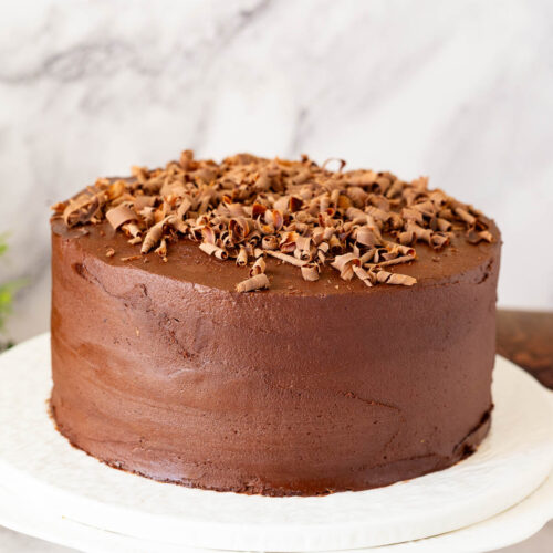 A cake stand with frosted chocolate cake.