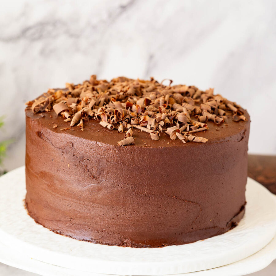 A cake stand with frosted chocolate cake.
