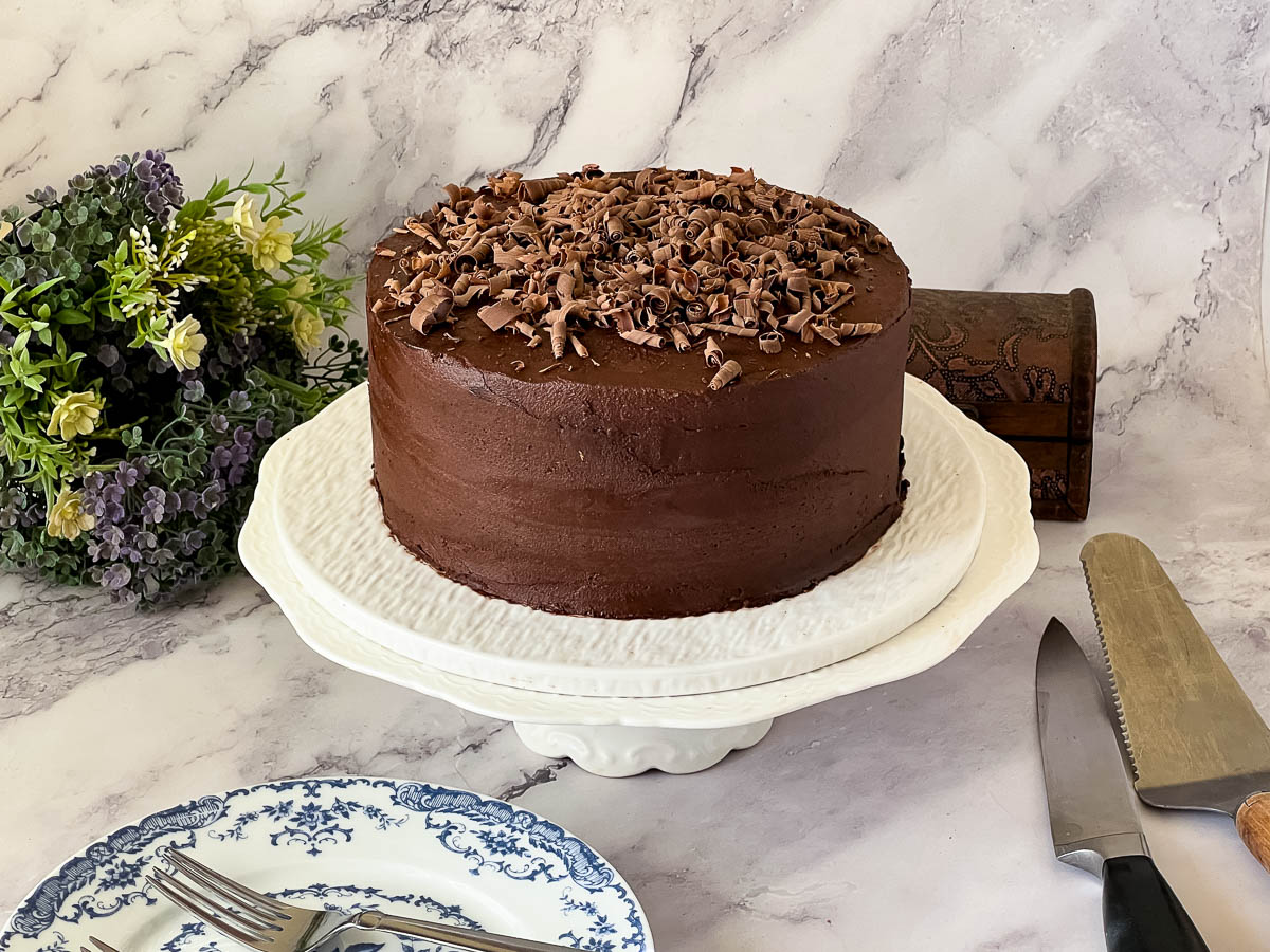 A frosted chocolate cake on the cake stand.