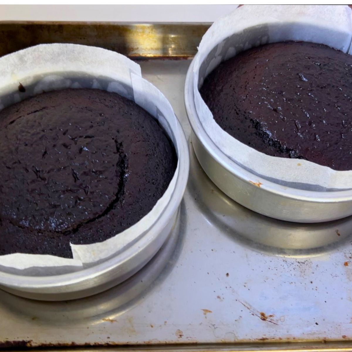 Two baked cakes in cake pans.