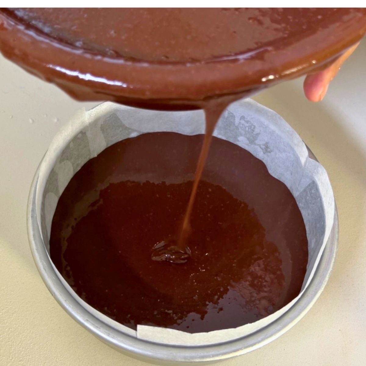 Pouring chocolate batter into the cake pan.
