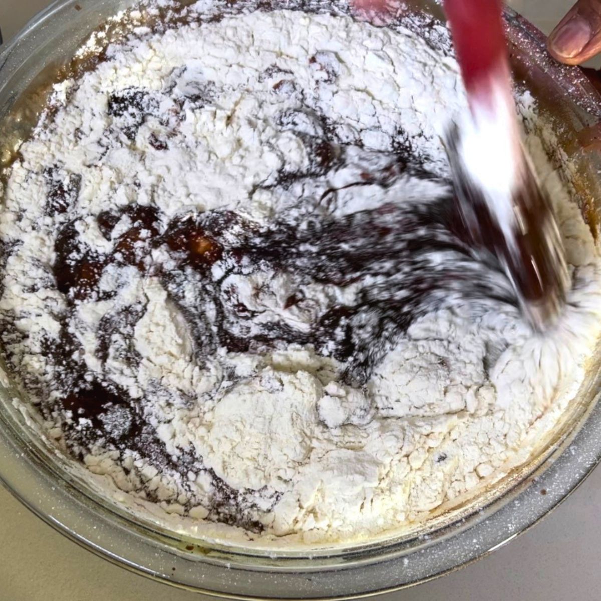Adding flour to the chocolate cake batter.