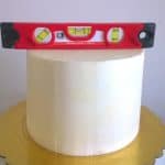 A buttercream frosted cake with a leveler.