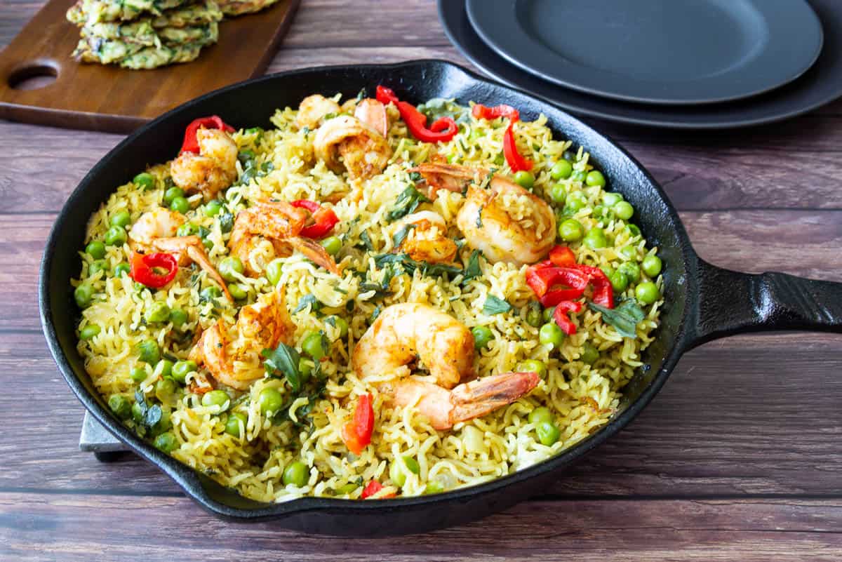 A skillet with turmeric rice and prawns.