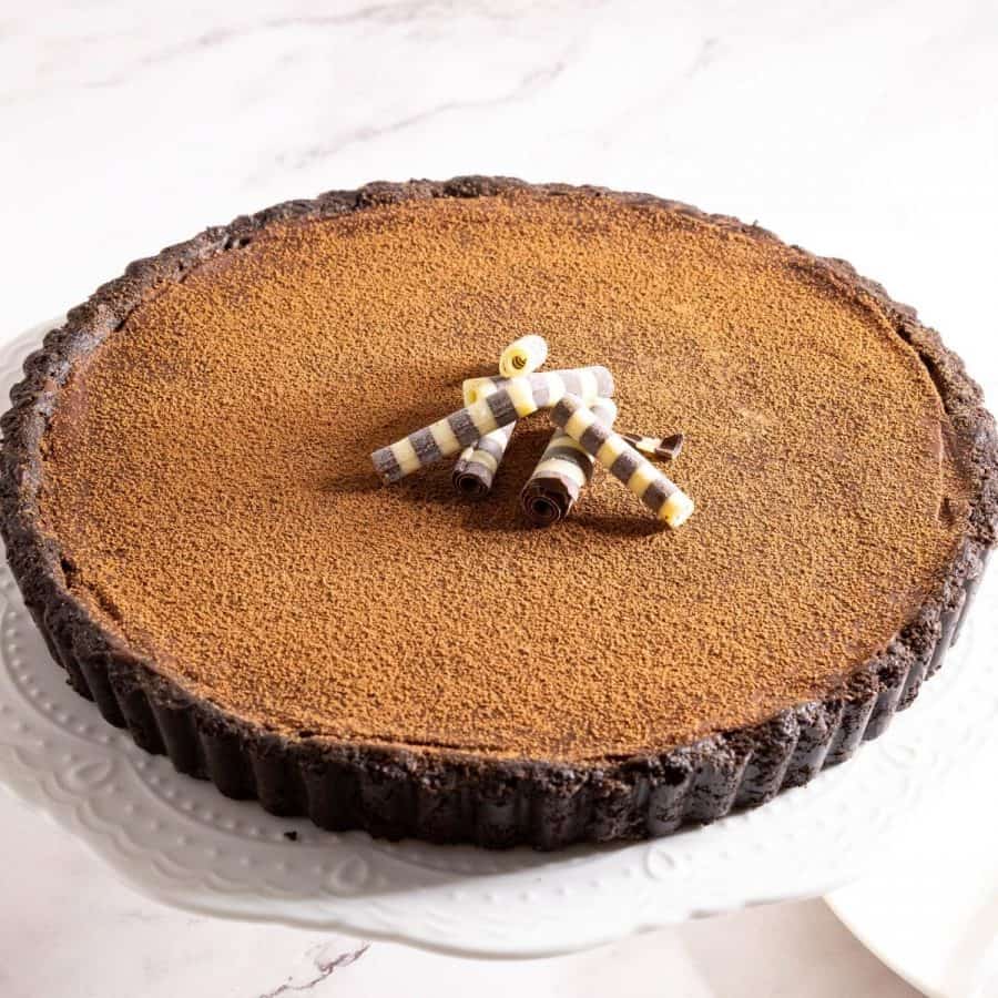 A ganache tart on the with chocolate curls.