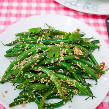A plate with green beans and sesame seeds.