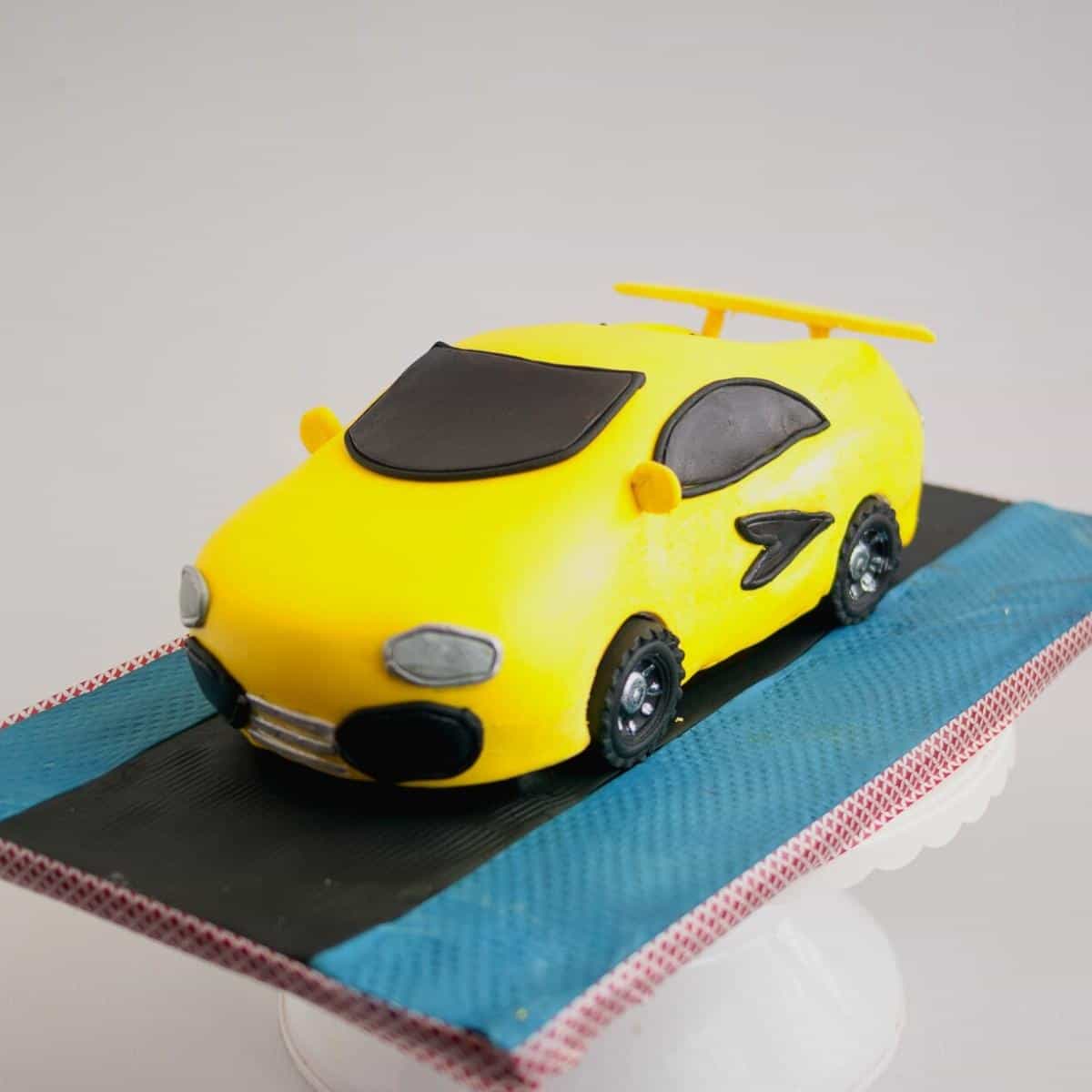 A cake board with a yellow car cake.