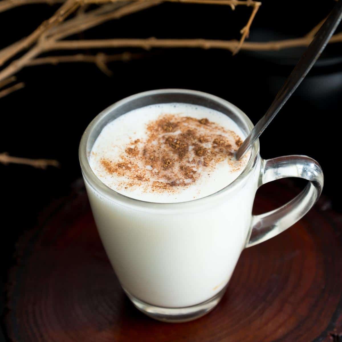 A glass cup with eggnog sprinkled with cinnamon