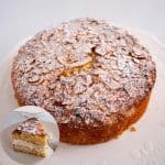 A coconut cake on a table dusted with powdered sugar.