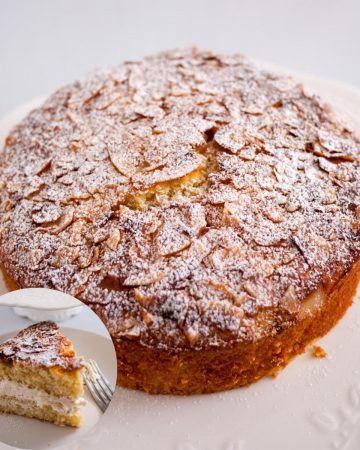 A coconut cake on a table dusted with powdered sugar.