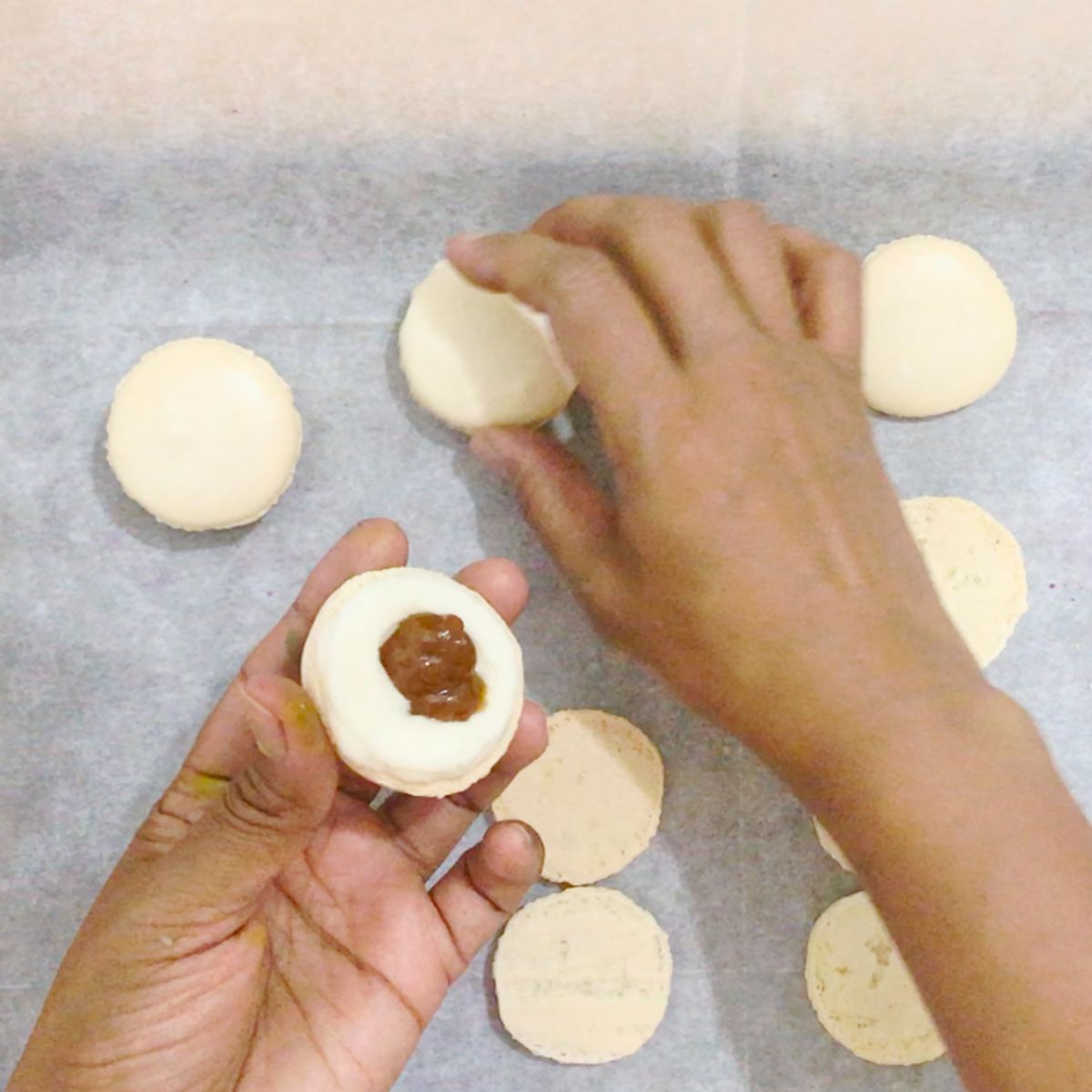 Filling the macarons with jam and frosting.