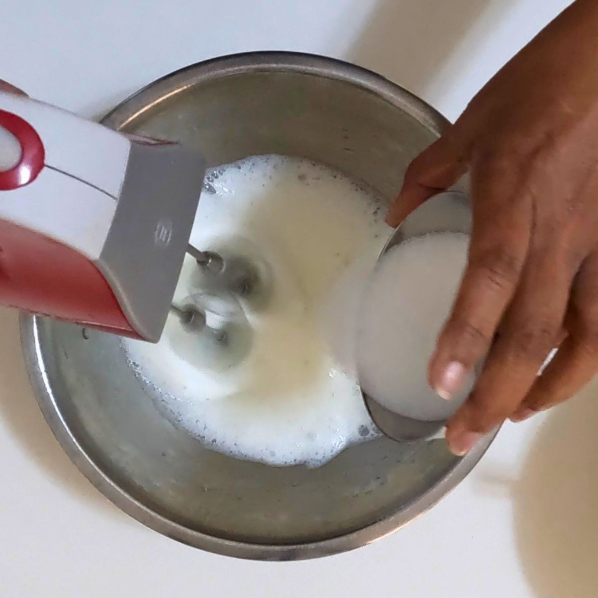 Adding sugar to the whipped egg whites.