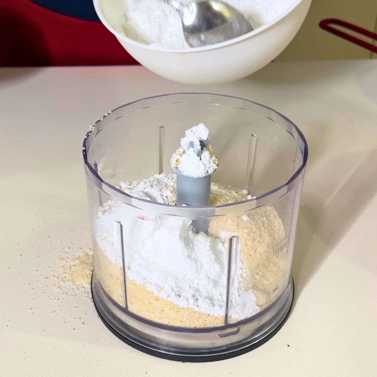 A food processor with almond flour and powdered sugar.