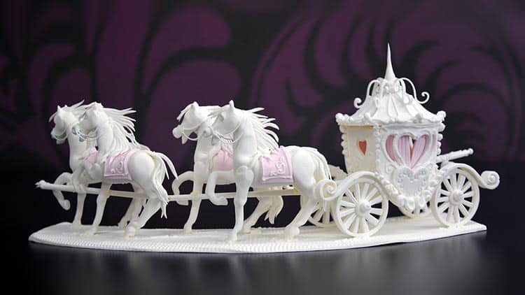A cake decorated like a carriage with horses.