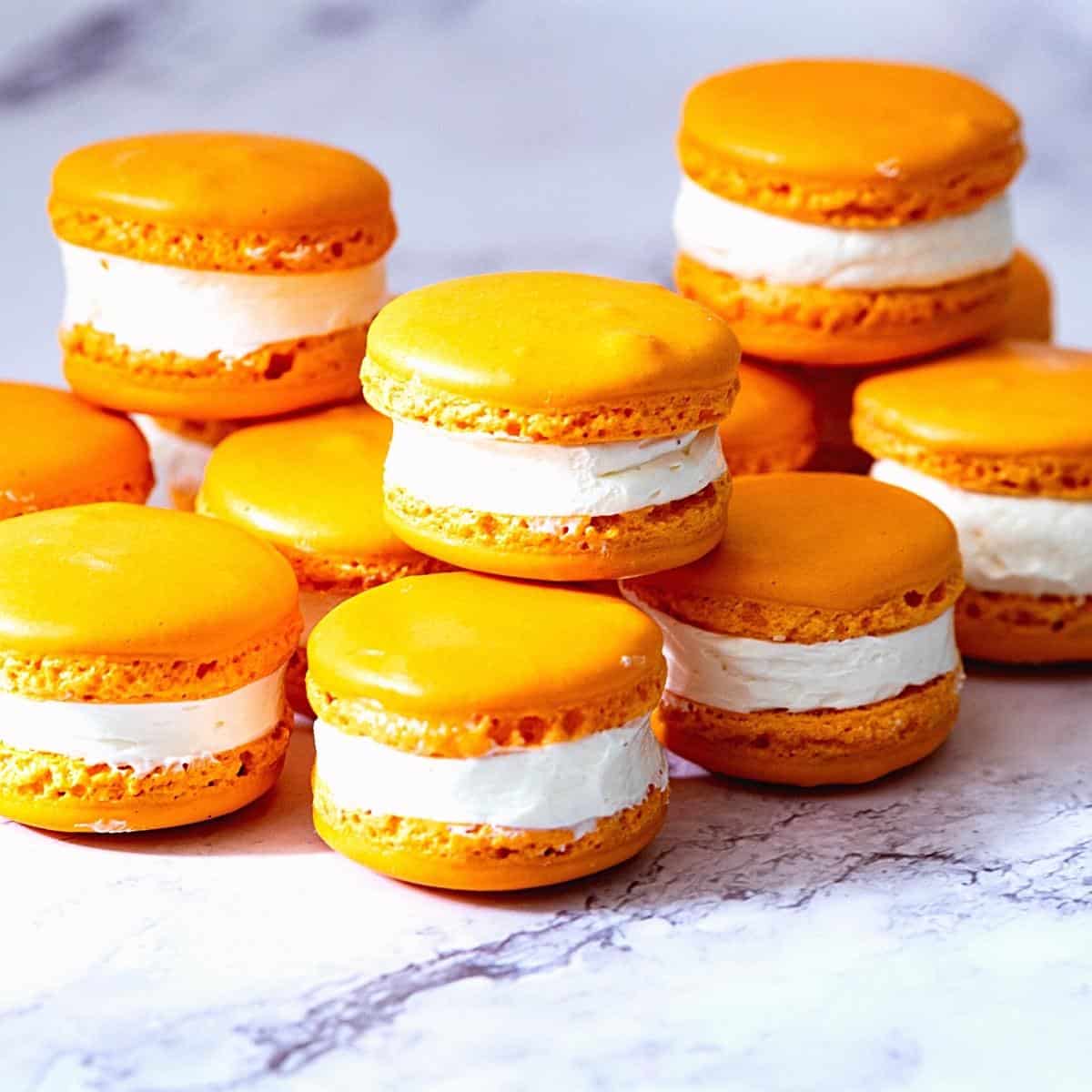 Stack of orange color macarons on the table.