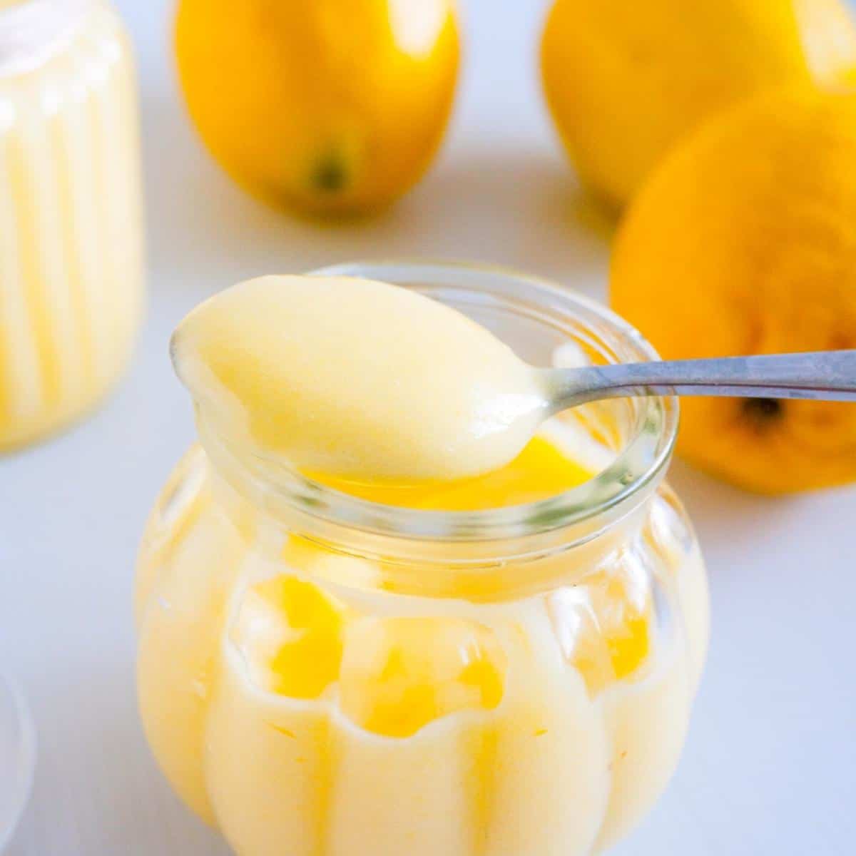 A spoon and mason jar with lemon fruit curd.