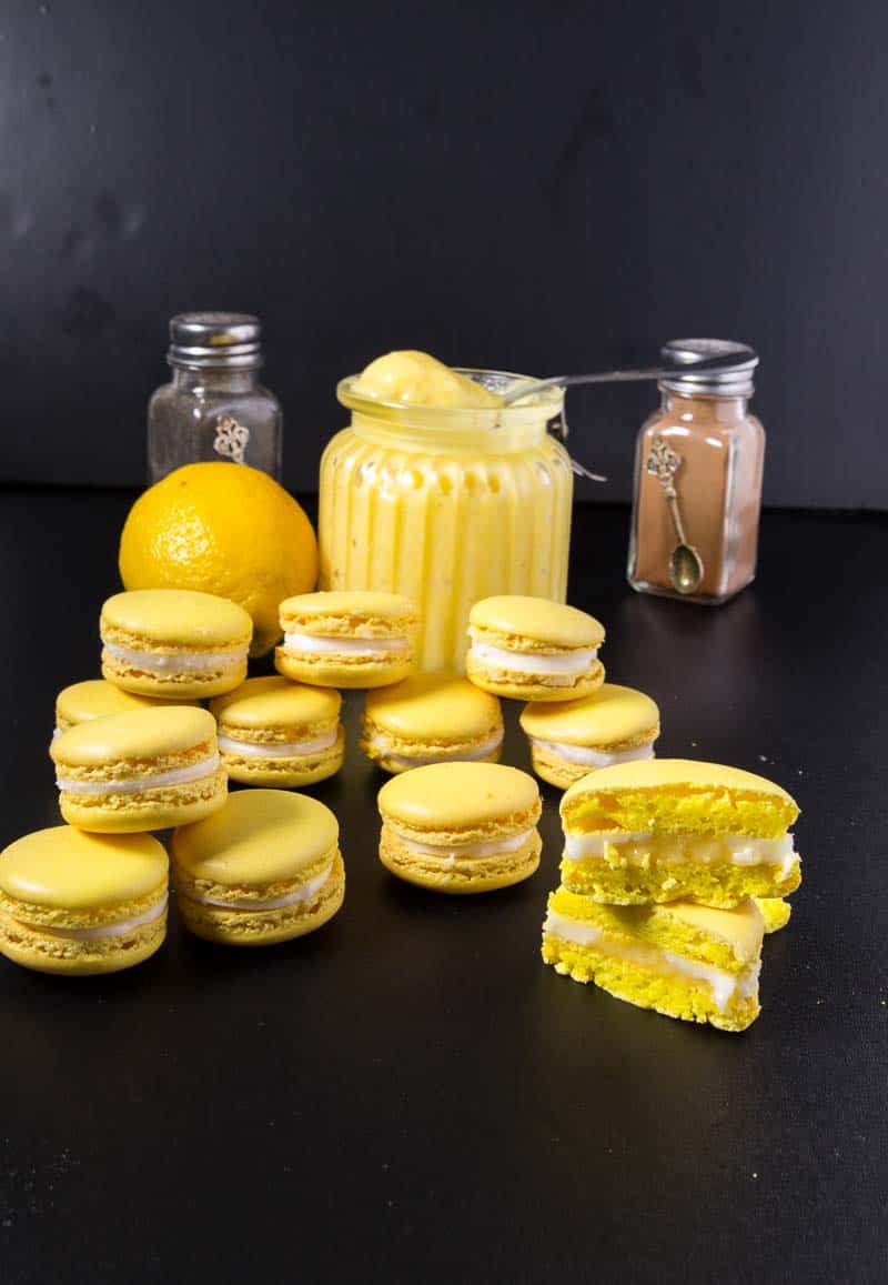 Lemon curd in a jar next to lemon macarons.