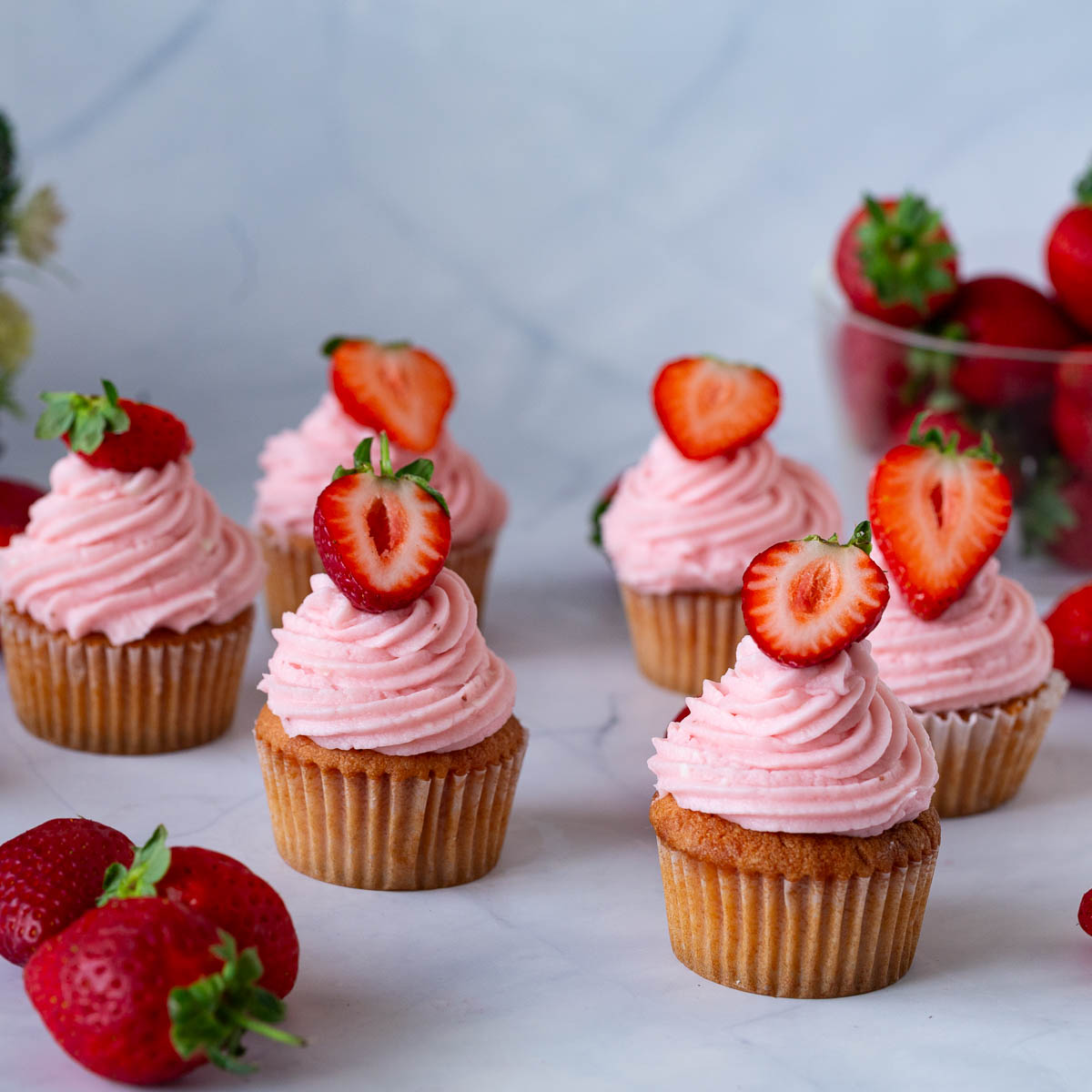 Frosted strawberry cupcakes on the table.